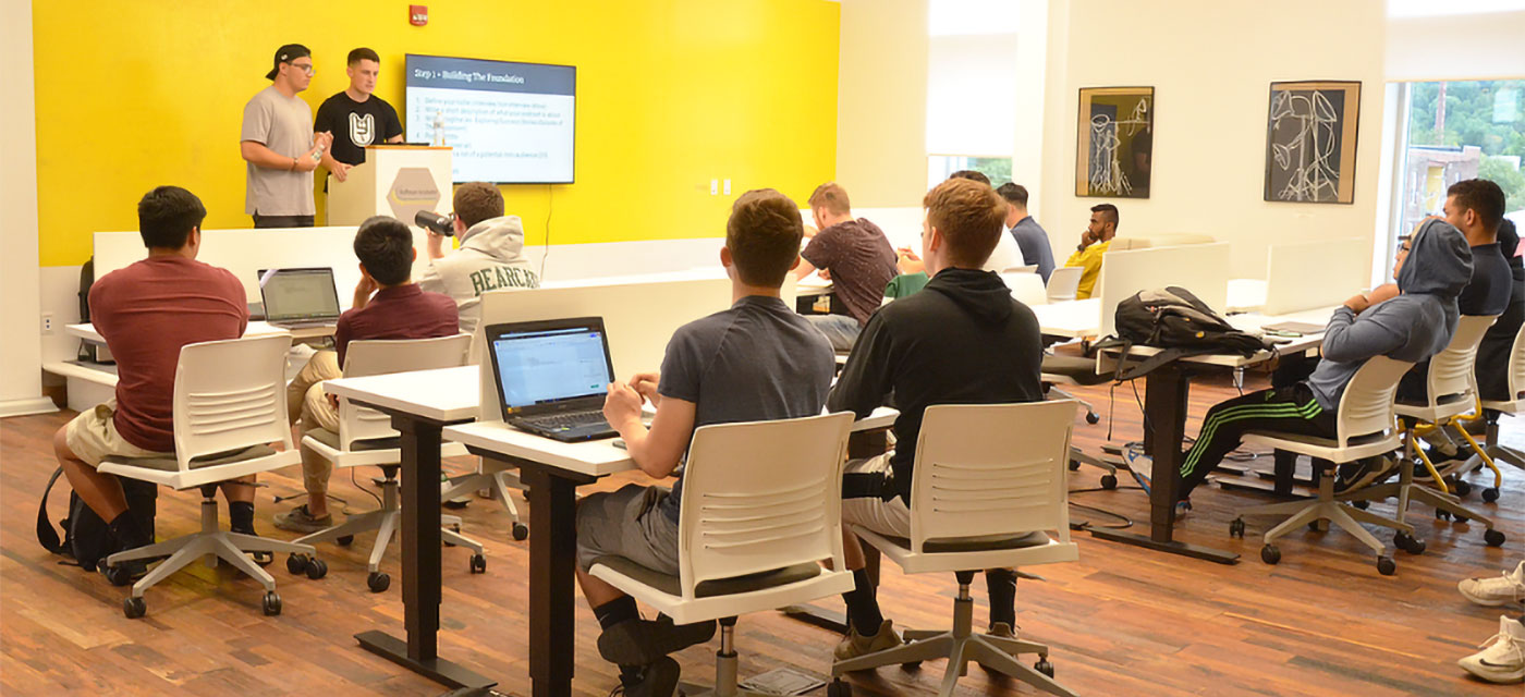 Two students give a presentation to a classroom full of other students.