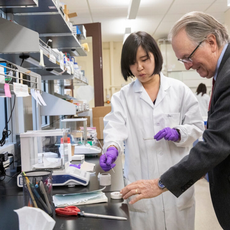 Person in a lab coat reviews material with a faculty member.